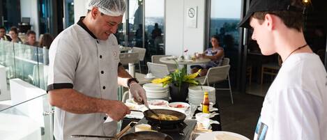 A chef preparing food in a modern kitchen with a view of the ocean.