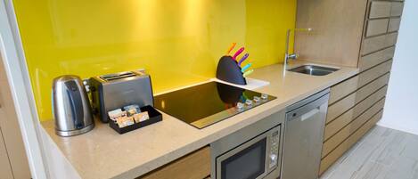 A modern kitchen with a yellow backsplash, stainless steel appliances, and wooden cabinetry.