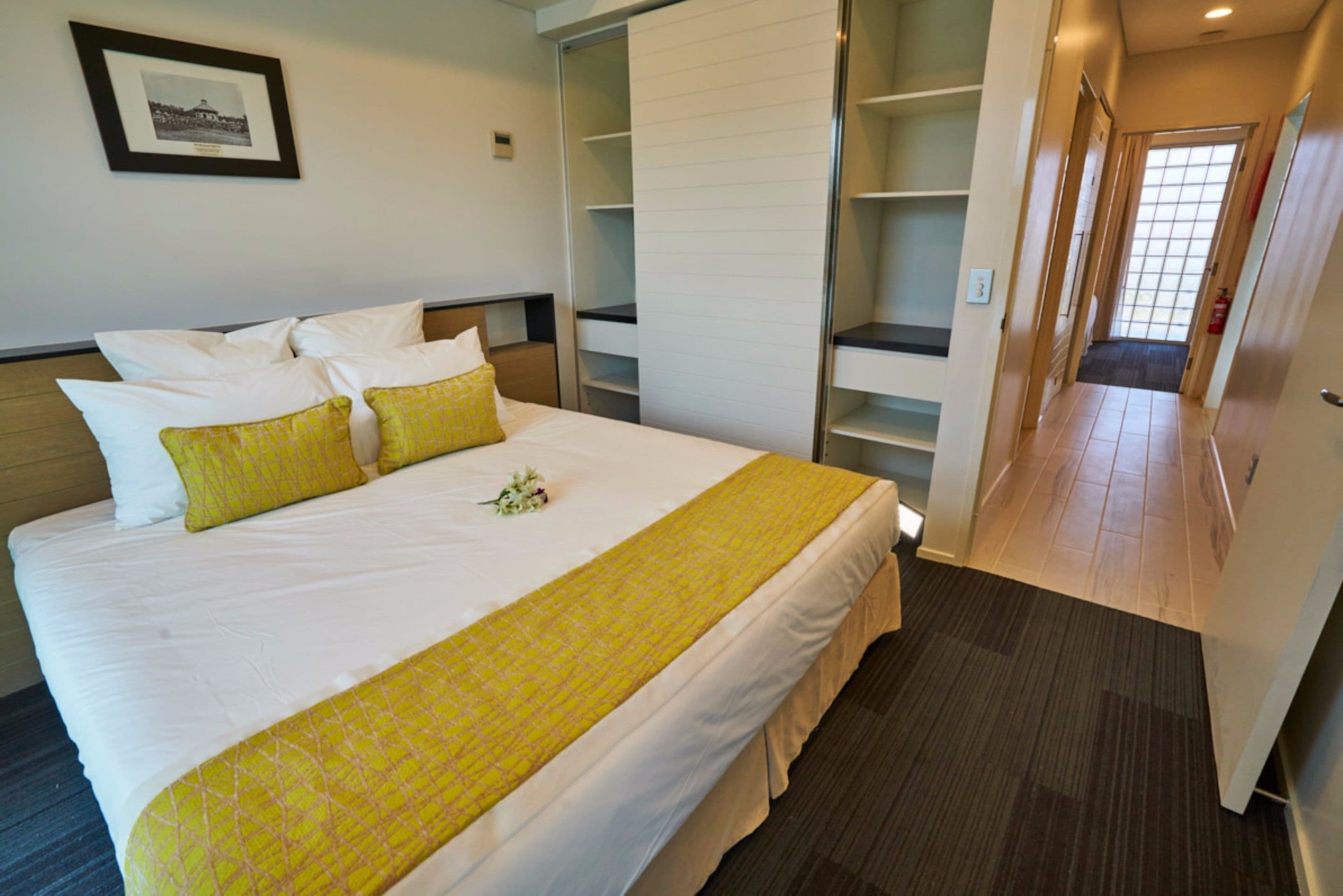 A hotel room with a large bed, a wardrobe, and a hallway.