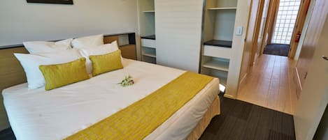 Habitación de hotel con una cama grande, un armario y un pasillo.