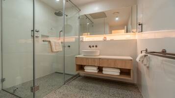 A modern bathroom with a glass shower enclosure, a wooden vanity, and a large mirror.