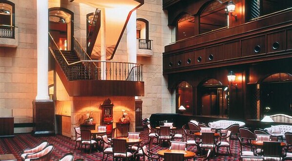 A spacious lobby with a grand staircase, multiple seating areas, and a large chandelier.
