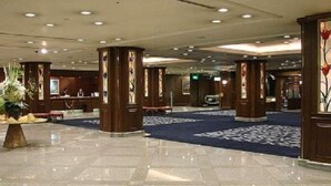 Un hall d’entrée spacieux, doté d’un sol carrelé brillant, de piliers en bois et d’une moquette bleue.