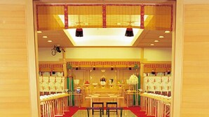 Une pièce de style japonais traditionnel, avec un sol recouvert de tatamis, une table basse avec des coussins et un tapis rouge menant à l’entrée.