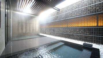 Un área de spa con jacuzzi, paredes de azulejos y una pared de piedra.