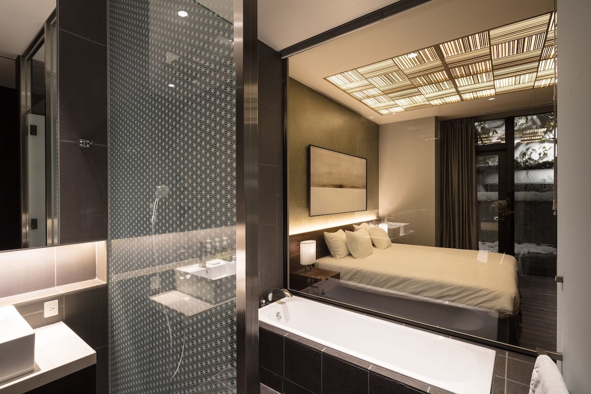 A modern bathroom with a glass shower enclosure, a large mirror, and a separate vanity area.