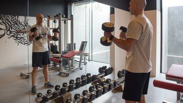 A gym with weightlifting equipment, benches, and a mirror.