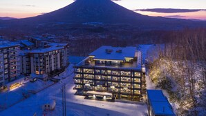 A modern hotel with multiple floors and a central atrium, surrounded by snow-covered buildings and a mountain in the background.