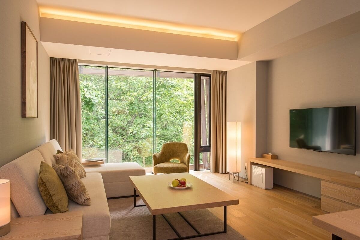 A modern living room with a sofa, armchair, coffee table, and TV.