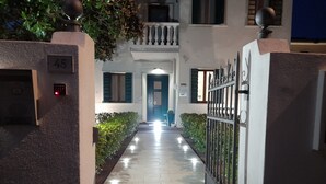 Un sendero bien iluminado que lleva a un edificio con una puerta azul, un cartel con el número 45 y un teclado de seguridad.