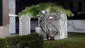 Un jardín con una pérgola, una zona de estar pequeña y un sendero.