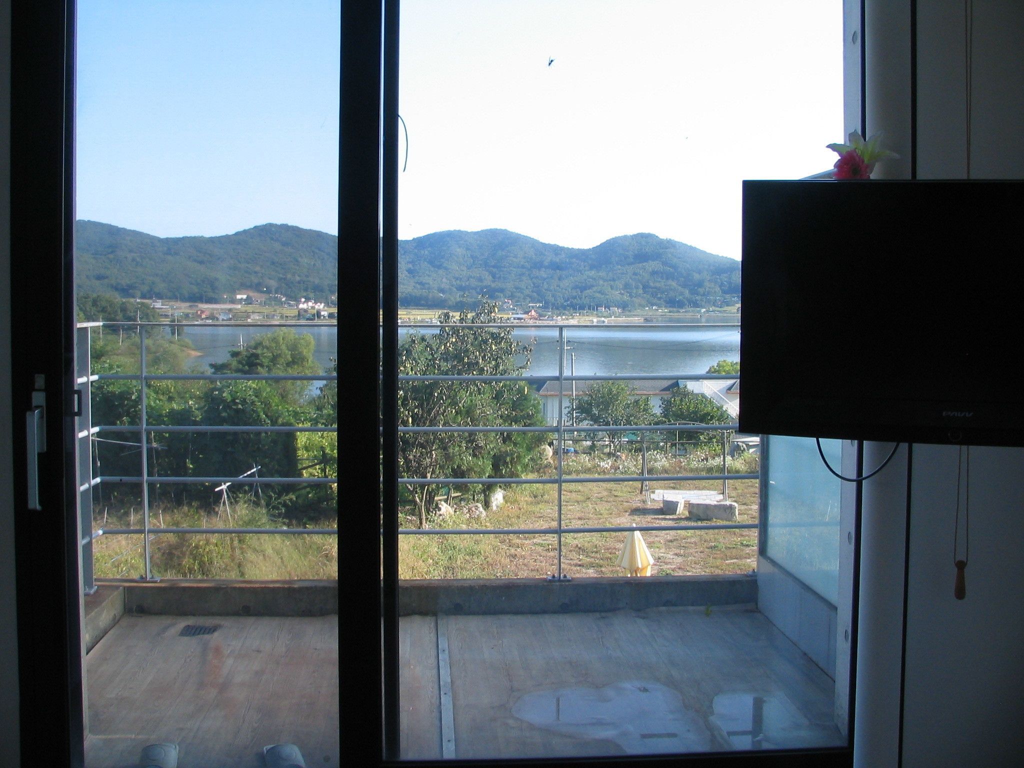 A balcony with a view of a lake, mountains, and a cityscape.