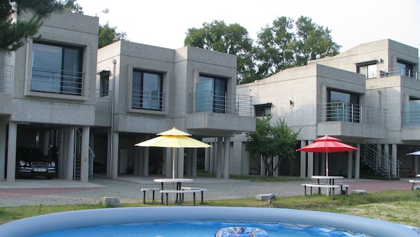 Un edificio moderno con piscina, mesas exteriores y sombrillas.