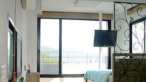 Un dormitorio moderno con cama, televisor y balcón con vistas.