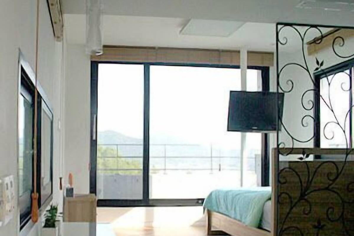 A modern bedroom with a bed, a TV, and a balcony with a view.