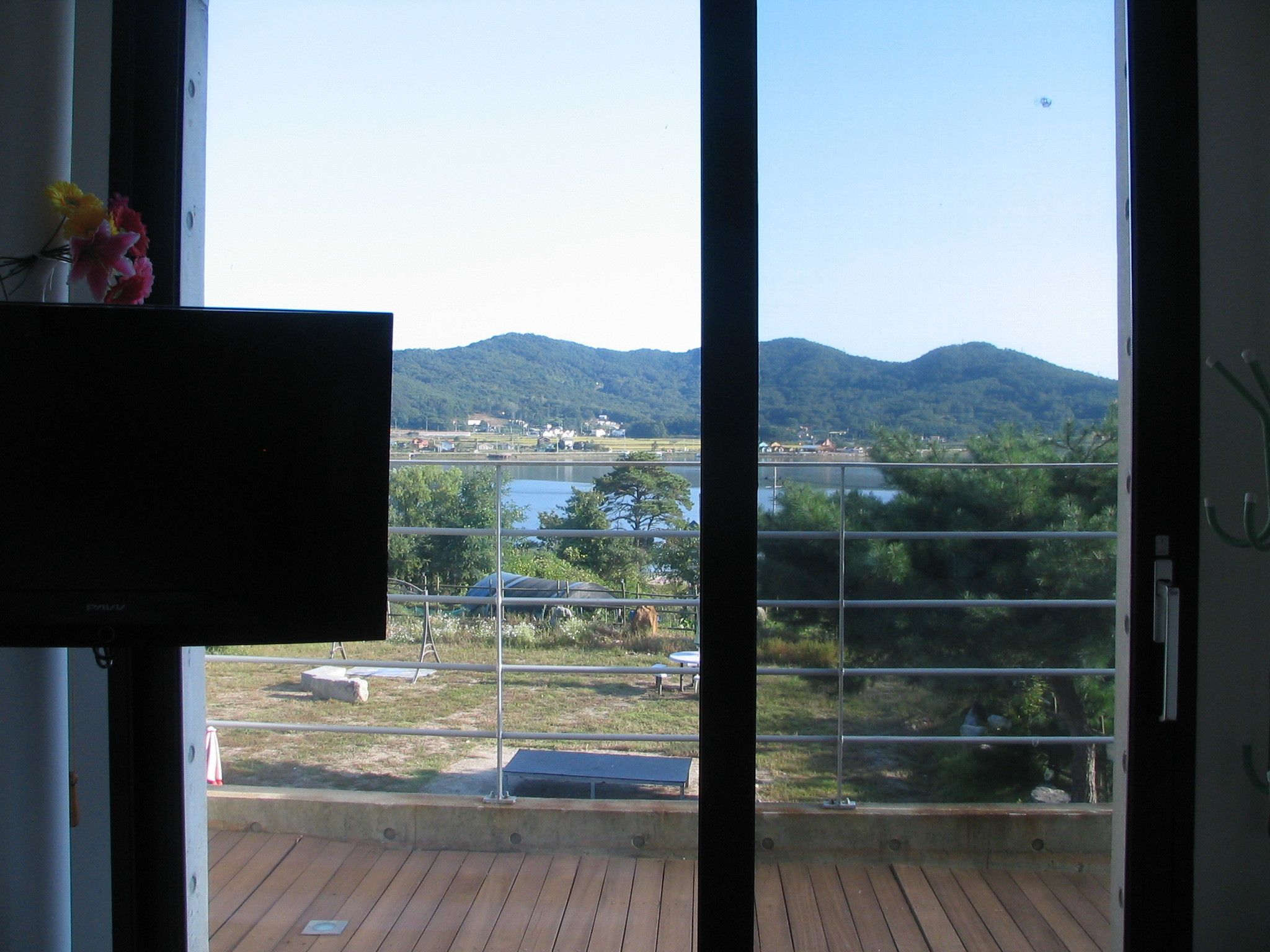 A room with a large window offering a view of a lake, mountains, and a distant town.