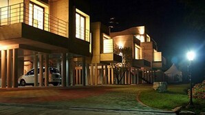 Un edificio moderno con zona de estacionamiento techada y entrada bien iluminada.
