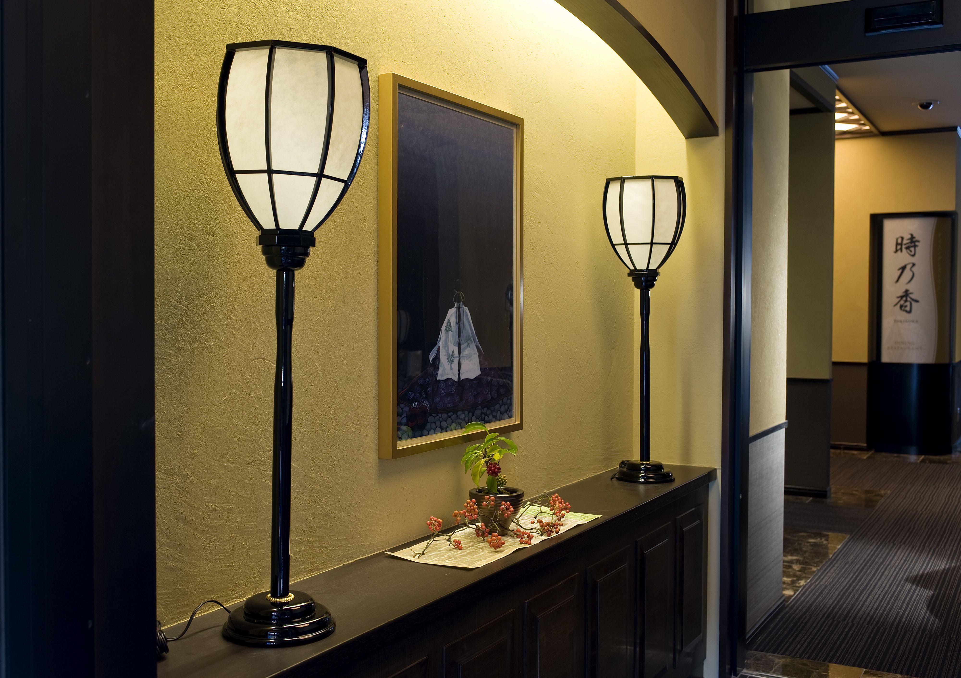 Um corredor com duas luminárias na parede e um quadro emoldurado.