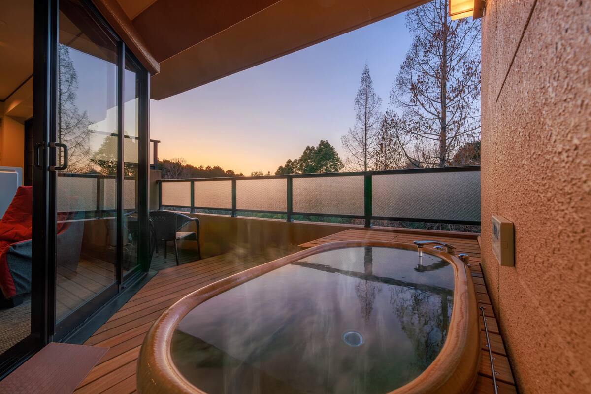 Un jacuzzi en una terraza de madera con puertas de vidrio que dan a un balcón.