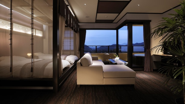 A modern hotel room with a balcony, a bed, a sofa, and a dining area. - Saiounomiya (Ise)