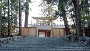A set of stone steps leading to a wooden entrance gate, surrounded by tall trees. - Saiounomiya (Ise)