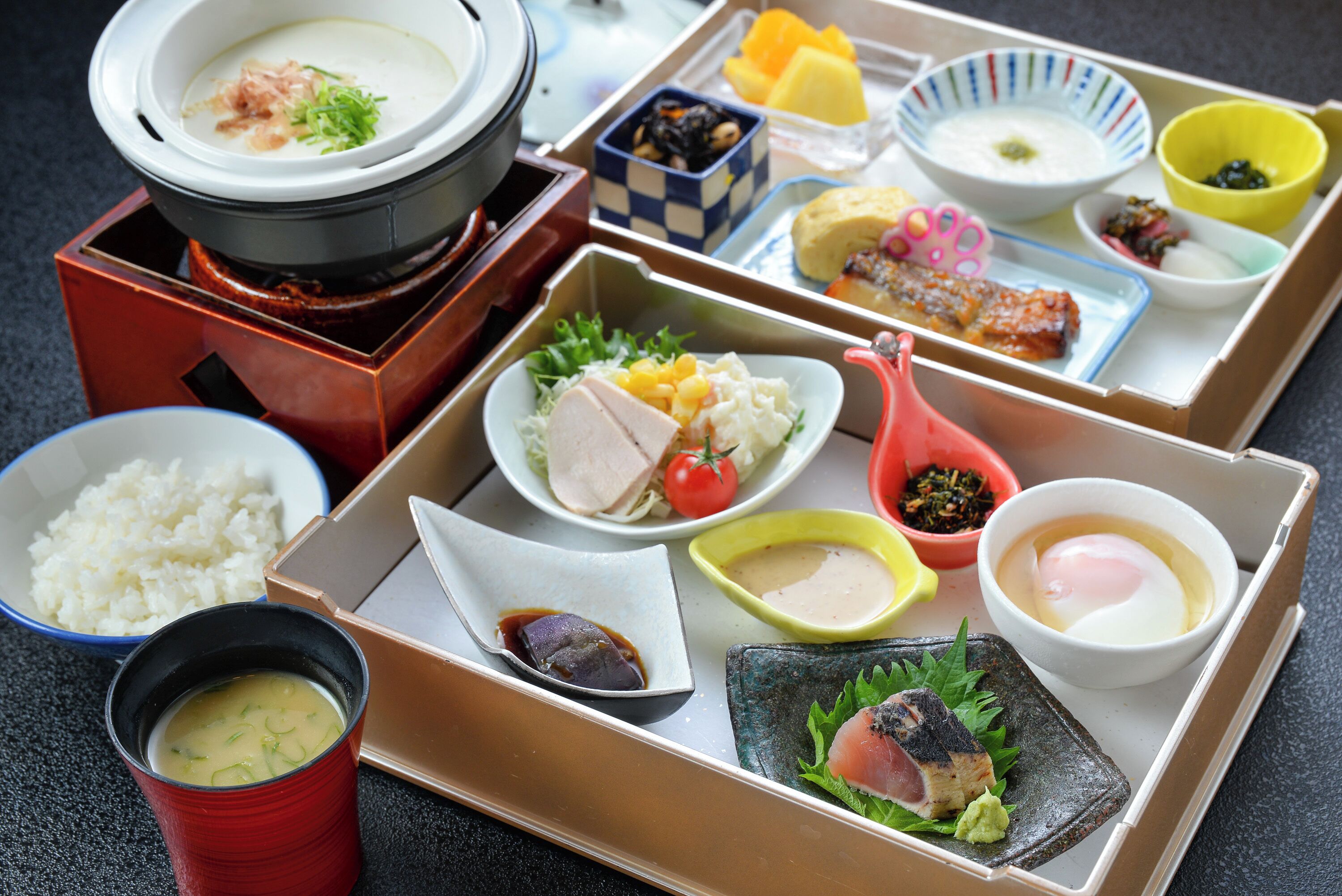Variedad de platos japoneses dispuestos en una mesa, incluyendo arroz, sopa y sashimi.