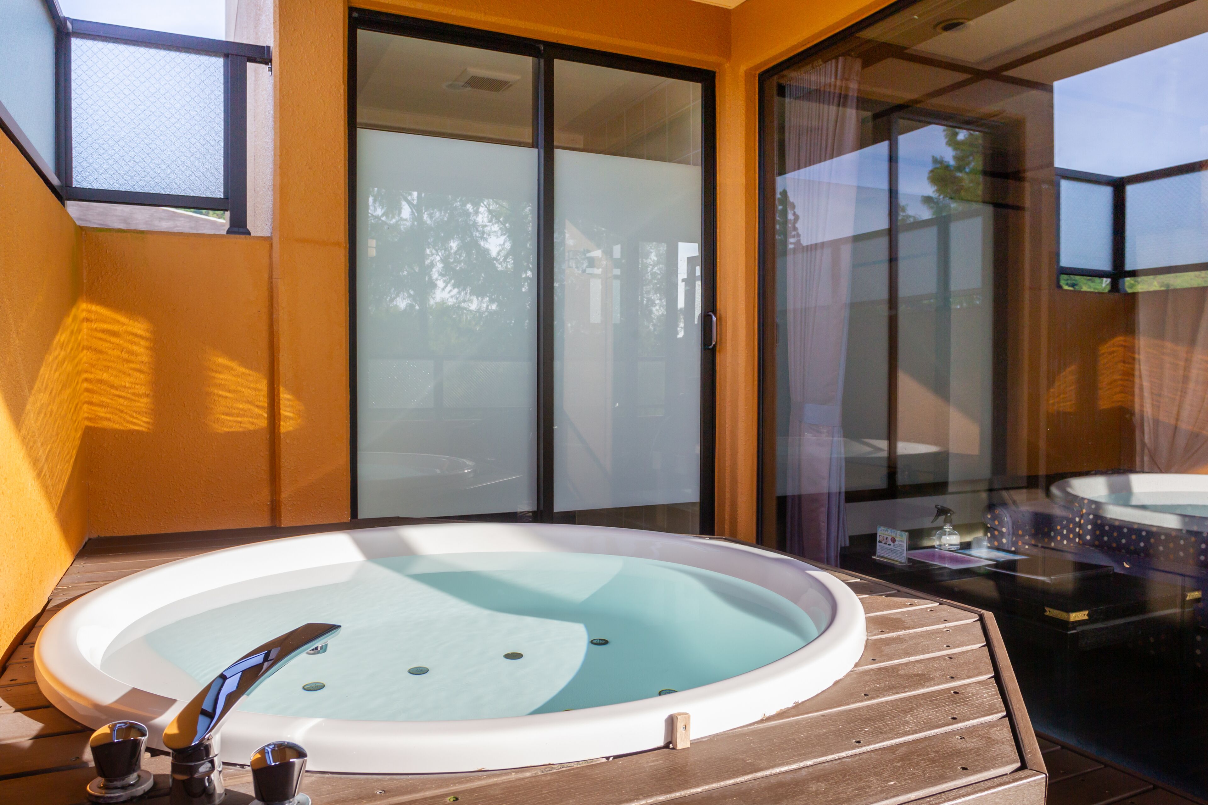 A hot tub on a wooden deck with glass doors and windows.