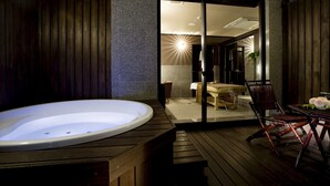 A spa area with a hot tub, wooden deck, and a glimpse of a bedroom with a bed and a nightstand. - Saiounomiya (Ise)