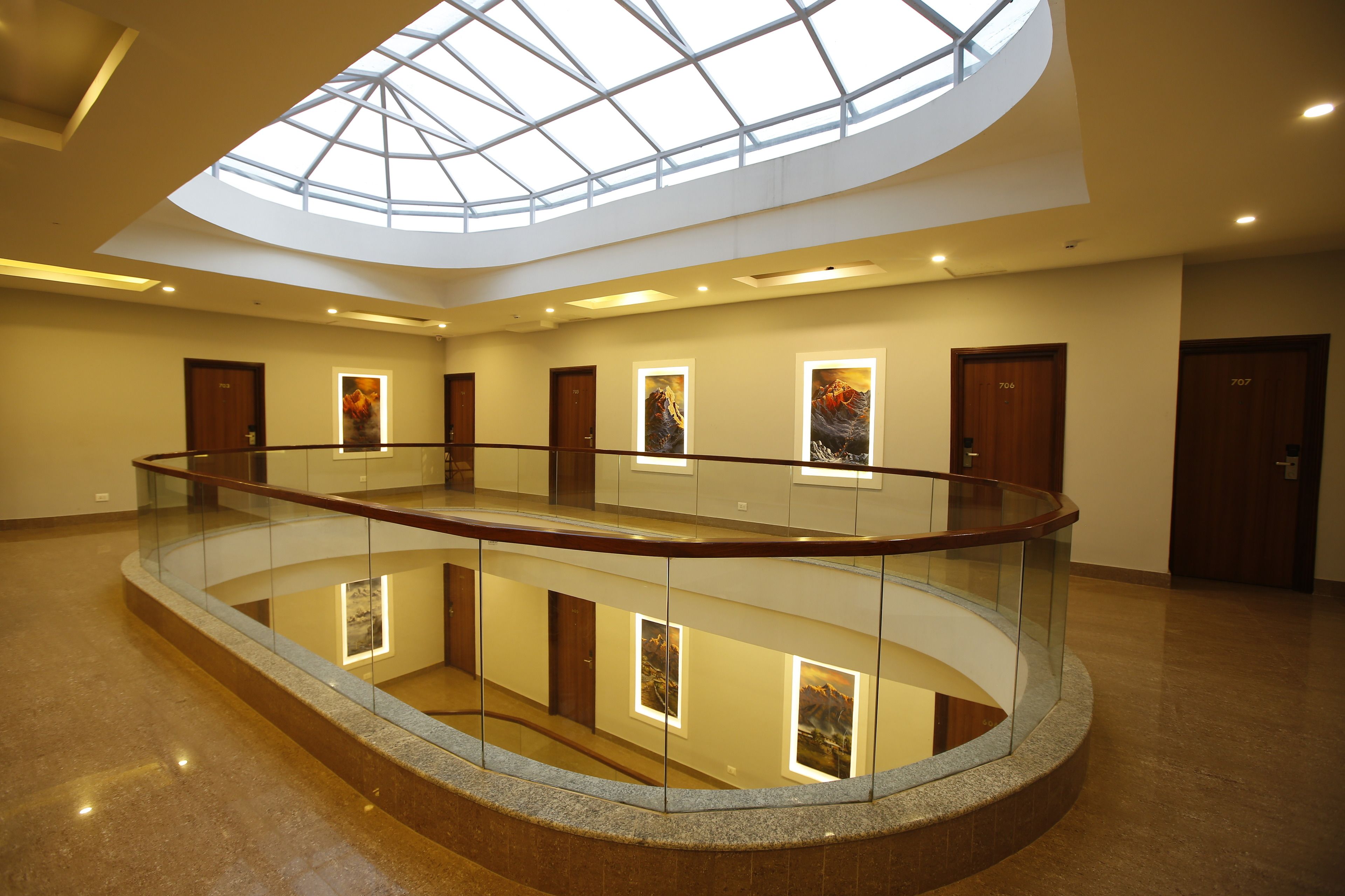 A spacious atrium with a glass railing, a skylight, and artwork on the walls.
