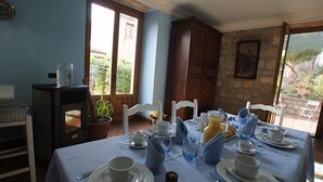 Un comedor con una mesa lista para el desayuno, con platos, tazas y una jarra de jugo.