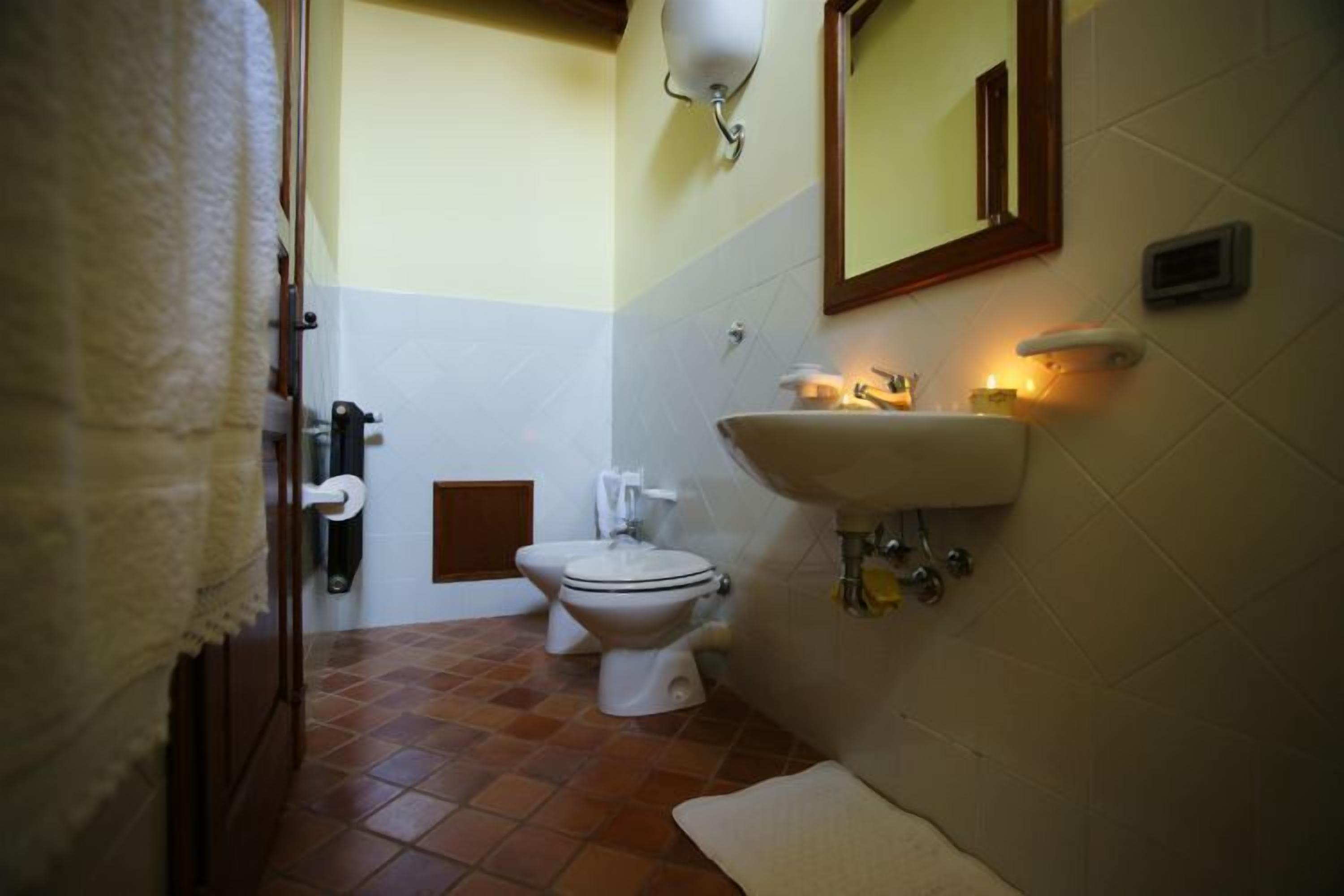 A bathroom with a toilet, sink, and mirror.