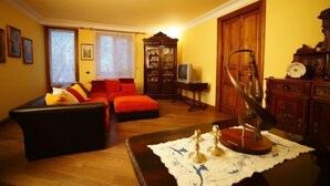 Una sala de estar con un sofá, un reposapiés y una mesa con objetos decorativos.