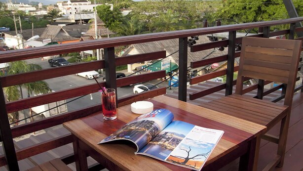 A wooden deck with a table and chair, a magazine, and a drink. - Krabi Orchid Hometel (Krabi)