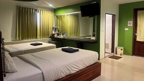 A hotel room with two beds, a TV, a desk with a chair, a mirror, and a door. - Krabi Orchid Hometel (Krabi)