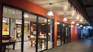 A corridor with glass doors leading to a dining area with tables and chairs. - Krabi Orchid Hometel (Krabi)