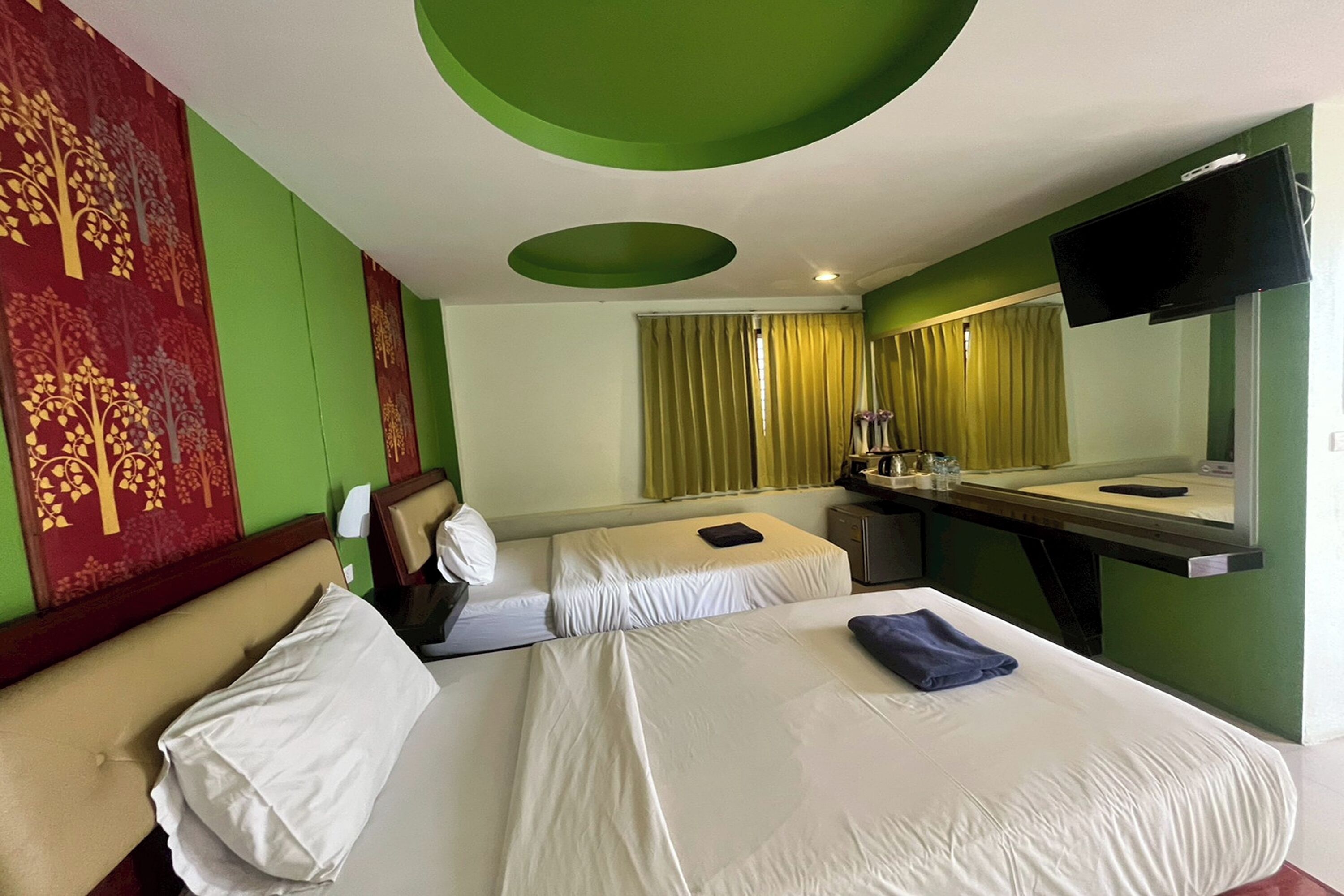 A hotel room with a bed, a desk, a chair, a television, and a window with curtains.