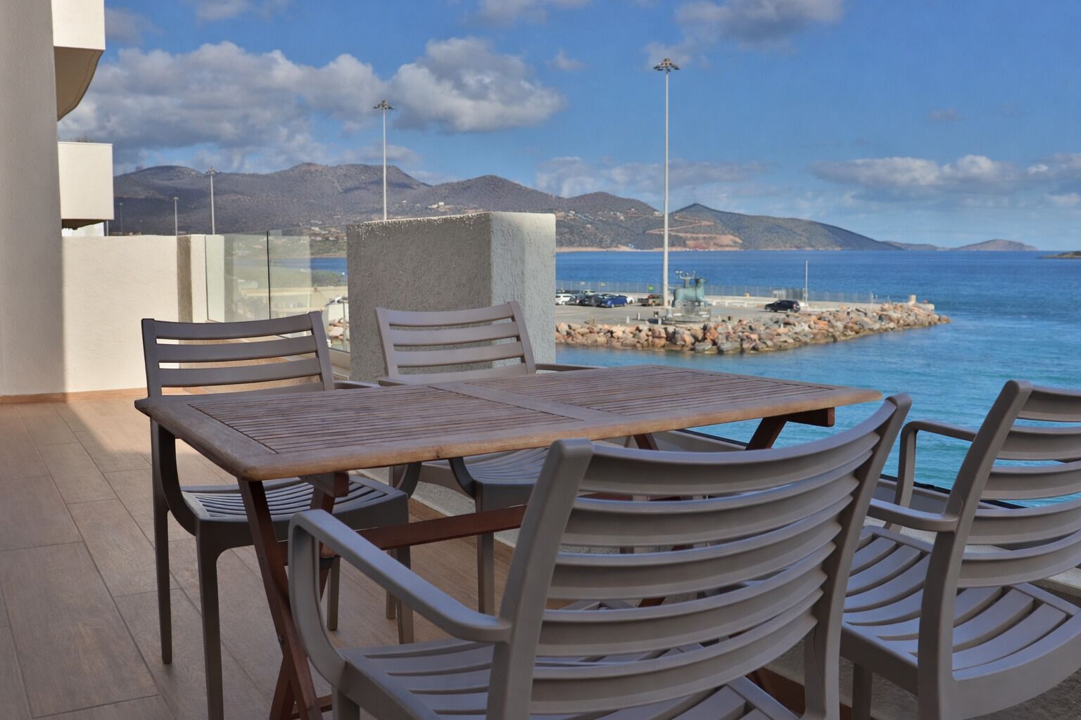 Una terraza con mesa y sillas, con vistas a la costa y montañas al fondo.