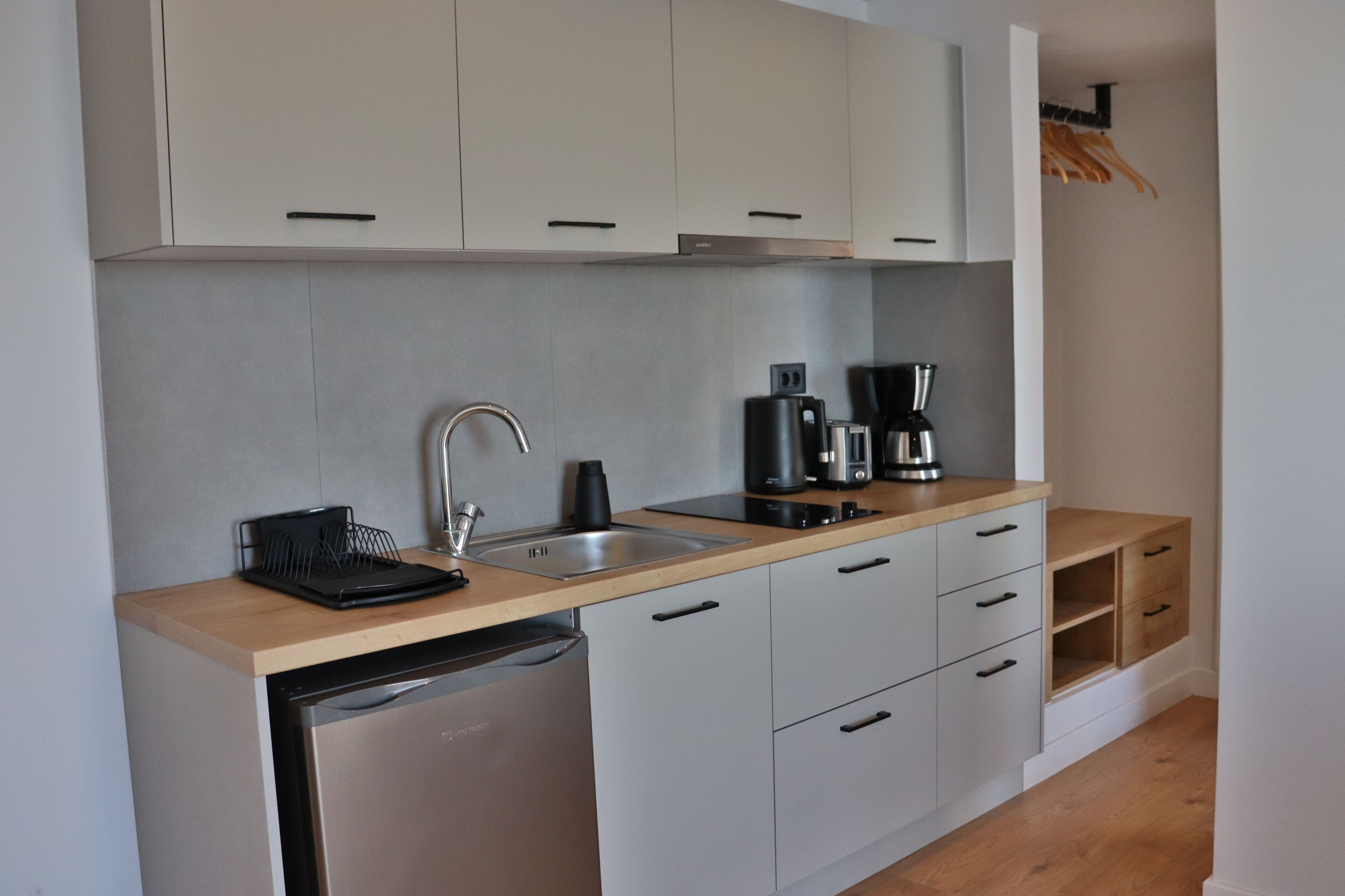 Una cocina moderna con armarios blancos, lavavajillas de acero inoxidable y una estación de café.