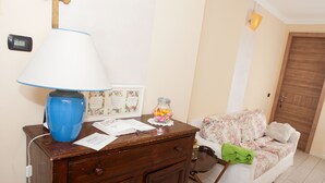A room with a wooden desk, a lamp, a floral sofa, and a wooden door. - Botton d'Oro Pelabrocco (Bergamo)