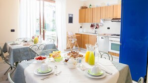 A dining area with a table set for breakfast, a kitchen with wooden cabinets, and a blue refrigerator. - Botton d'Oro Pelabrocco (Bergamo)