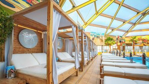 A sunlit indoor pool area with wooden loungers and a glass ceiling. - Hotel Knorz (Zirndorf)