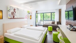 A modern hotel room with two beds, a dining area, and a balcony with a view of greenery. - Hotel Knorz (Zirndorf)