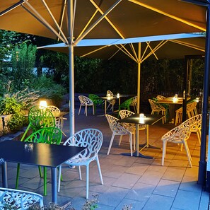 An outdoor patio area with tables and chairs under a canopy. - Hotel Knorz (Zirndorf)