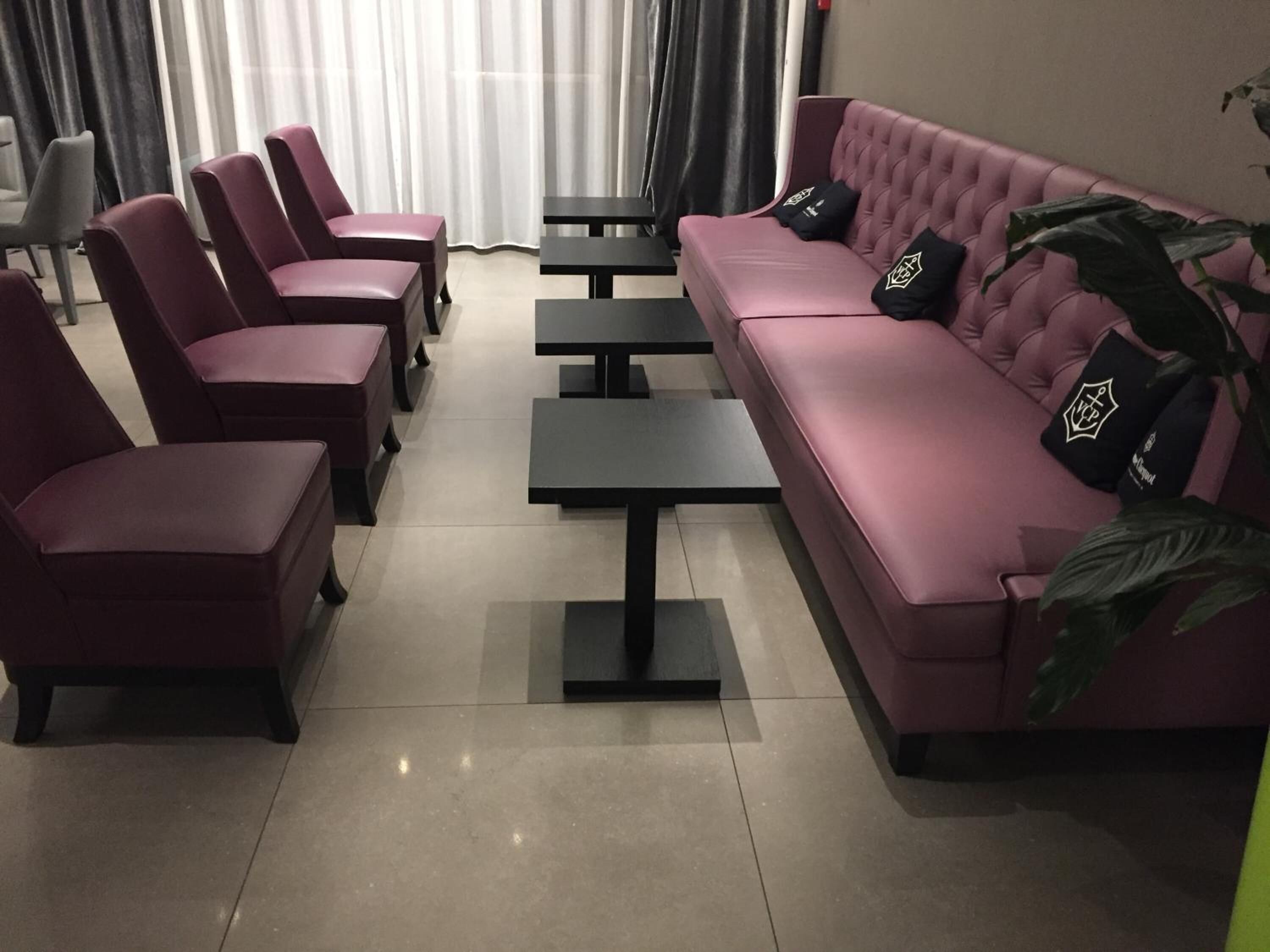 Et siddeområde med en lyserød sofa og matchende stole, et lille bord og en potteplante.