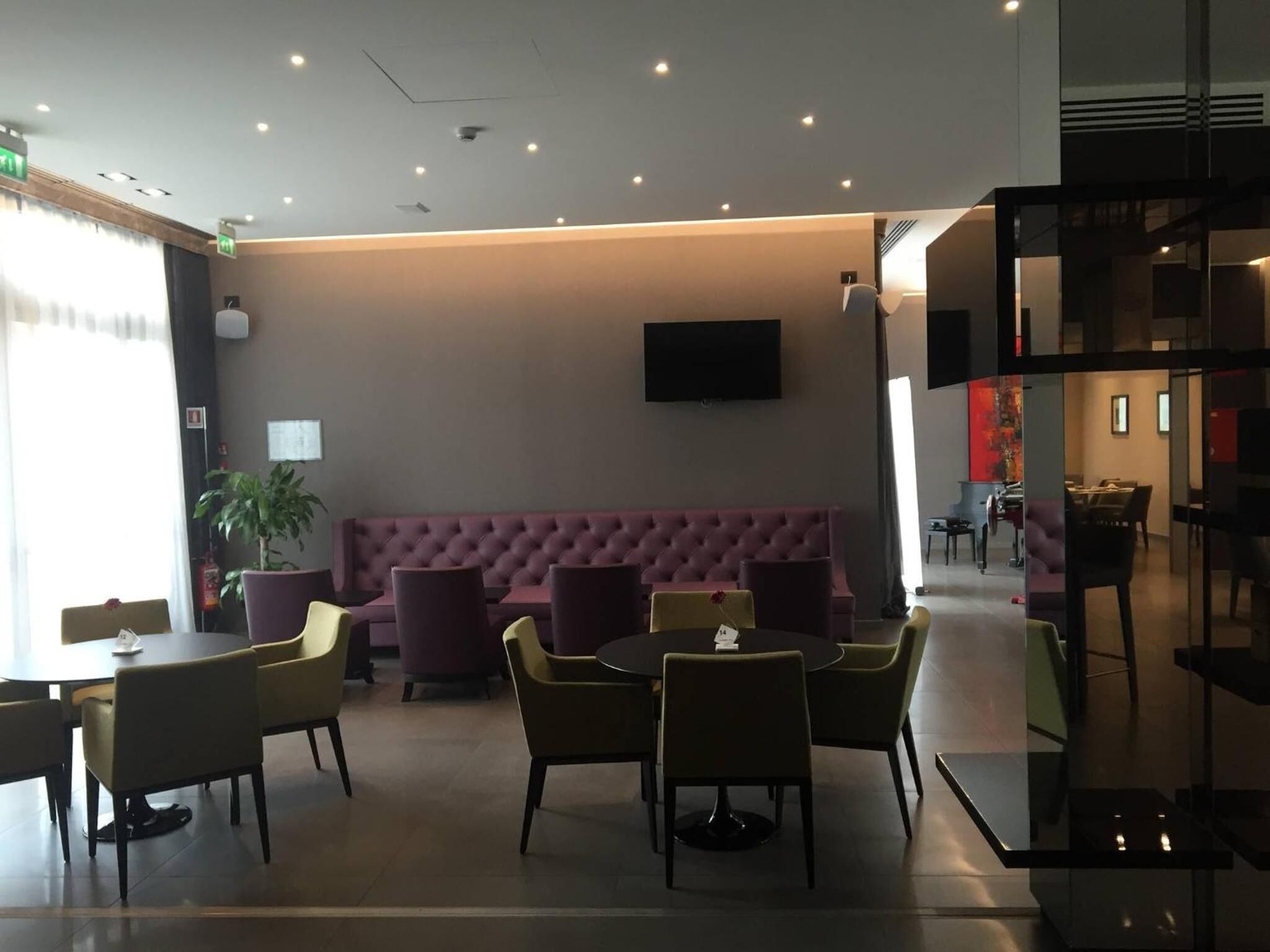 A modern lobby with a seating area, a flat-screen TV mounted on the wall, and a staircase to the right.