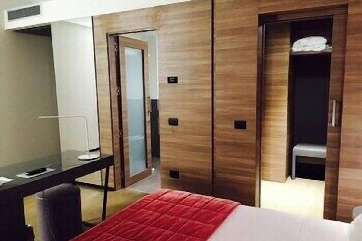 A hotel room with a bed, a desk, a chair, and a wardrobe.