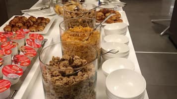 Un buffet proposant une variété de plats et de contenants, notamment des tartes, des pâtisseries et des yaourts.