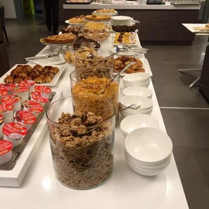 A buffet with various food items and containers, including pies, pastries, and yogurt.