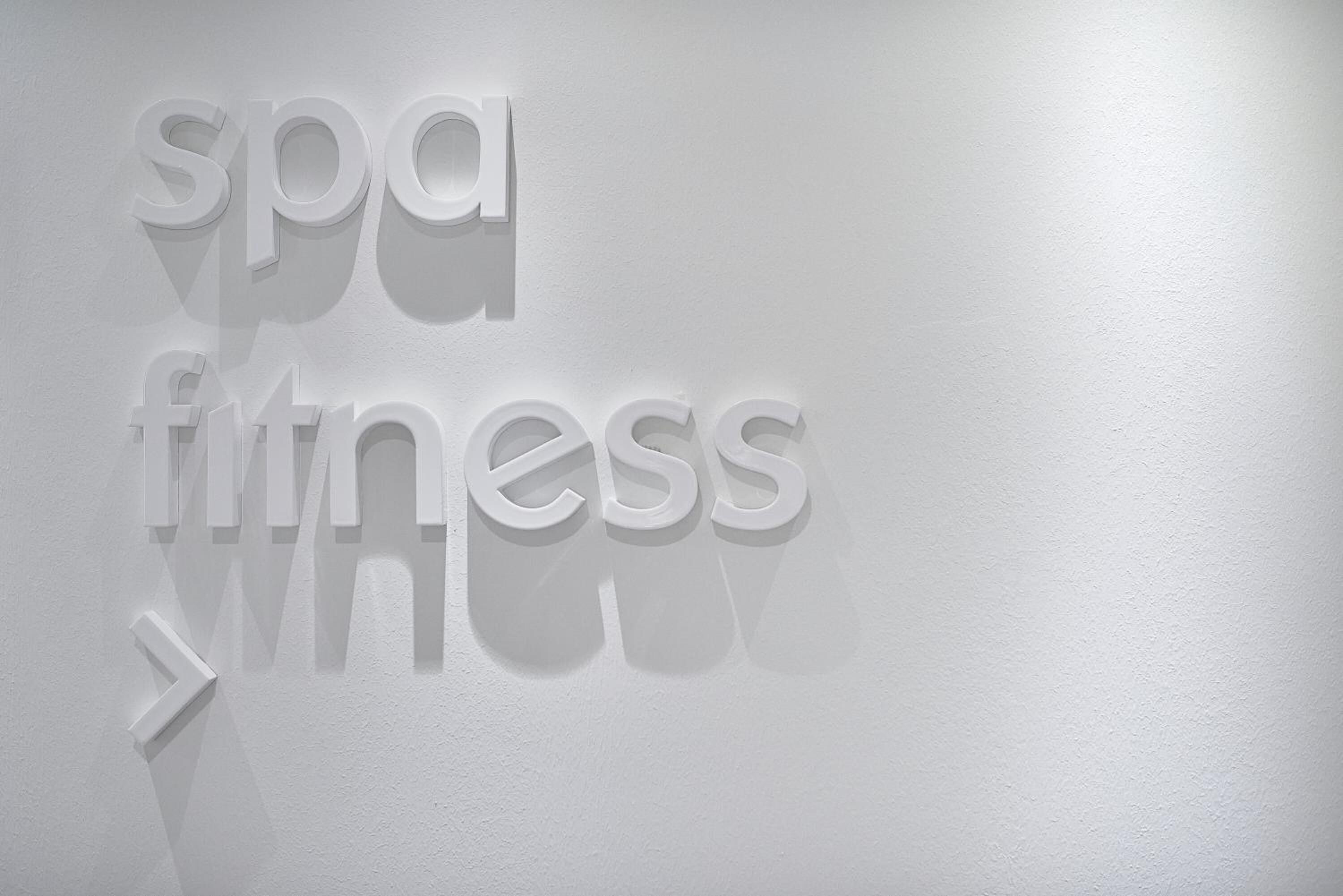 Un mur sur lequel on peut lire les mots « spa fitness » en lettres blanches en relief.
