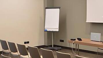 Ein Konferenzraum mit Reihen von Stühlen, einer Whiteboard-Tafel und einer Projektionsleinwand.